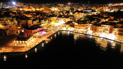 Fototapeta na wymiar Aerial drone night shot of iconic and picturesque illuminated Venetian old port of Chania with famous landmark lighthouse and shops - restaurants serving Cretan traditional food, Crete island, Greece