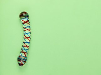 Beautiful evenly lit glass dildo on a plain green background with copy space.
