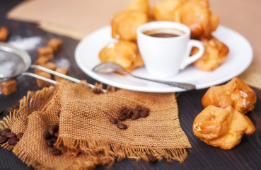 Cup of hot black coffee with home made profiteroles on a rustic table