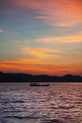 Landscape with a boat floating on the water. On the background of the contour of the shoreline and...