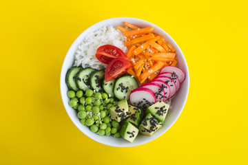 Vegan poke bowl with white rice and vegetables in the white  bowl in the center of the yellow...
