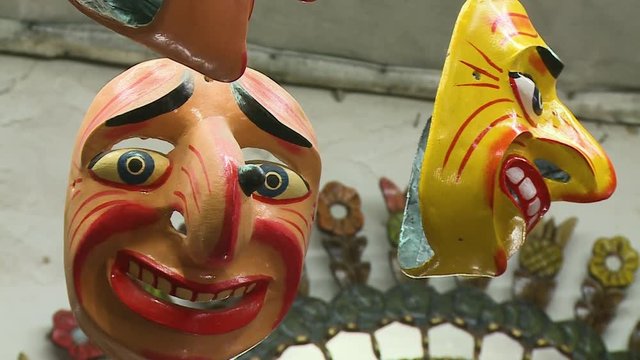 extreme close up low angle still shot of front and side-view of two funny smiling masks on display, San Blas, Cusco