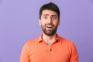 Excited shocked emotional young handsome bearded man posing isolated over violet purple wall background.