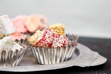 Set of various Turkish delight in traditional silver bowl on metal tray black background.Middle Eastern dessert.