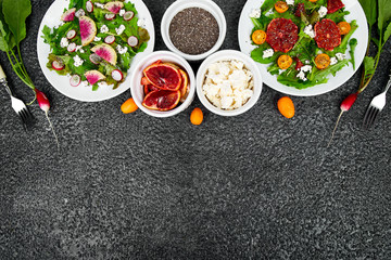 Mix salads on black background. Fresh Citrus Salad with arugula feta, chia, kumquat and blood orange.  Watermelon Radish salad. Vegan, vegetarian, clean eating, dieting, food concept. 