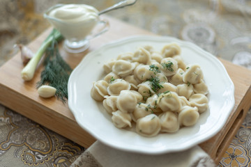 Boiled meat dumplings served with sour cream, garlic and onion. Traditional Russian pelmeni. 