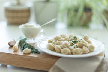 Boiled meat dumplings served with sour cream, garlic and onion. Traditional Russian pelmeni. 