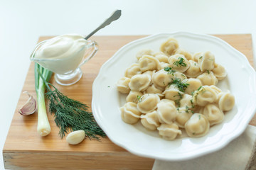 Boiled meat dumplings served with sour cream, garlic and onion. Traditional Russian pelmeni. 