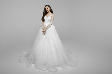 Splendid girl with curly hair in wedding dress, keeping a hand together, hairstyle, isolated on a...