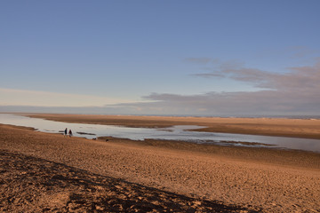 Białe pogodne chmury na niebieskim niebie ponad nadmorską plażą.