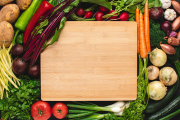 Empty Wood Cutting Board Mockup with Fresh Vegetables. Vegetarian Raw Food. Healthy Eating Concept with Copy Space.