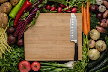 Kitchen Santoku Knife with Fresh Vegetables on Wood Cutting Board. Vegetarian Raw Food. Healthy Eating Concept.