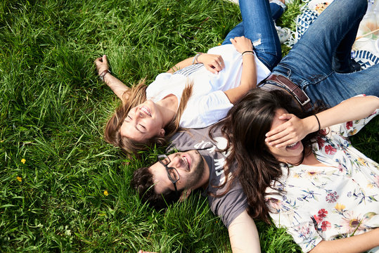 Top view of happy friends lying in a meadow in park