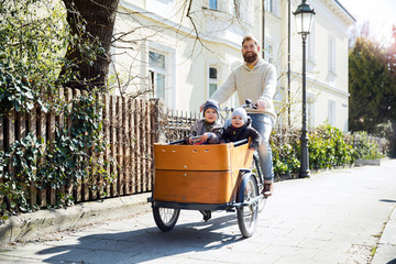 Happy father with two children riding cargo bike in the city