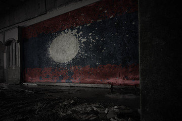 painted flag of laos on the dirty old wall in an abandoned ruined house.