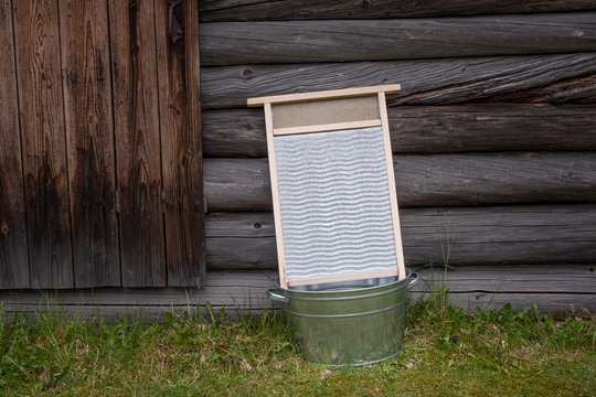 outdated Vintage washboard in a old zinc coated basin on the street near the wall of a wooden house