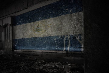 painted flag of nicaragua on the dirty old wall in an abandoned ruined house.