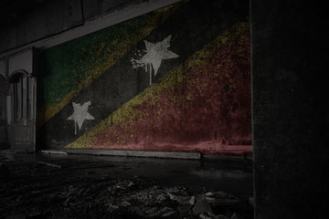 Fototapeta na wymiar painted flag of saint kitts and nevis on the dirty old wall in an abandoned ruined house.