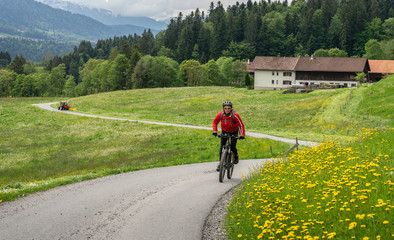 Fototapeta premium senior woman mountainbiking on a e-mountainbike in early spring, in the Allgaeu Area, a part of the bavarian alps,Germany