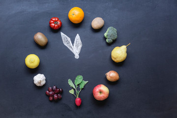 Fruits and vegetables building clock on dark ground with