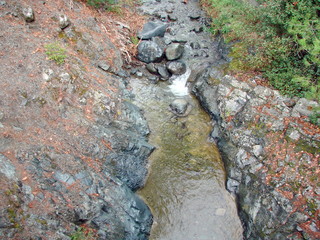 A view from the bridge to the swift flow of a transparent mountain river that breaks its way through the rocks that glow in the sun.