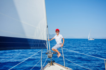 Little boy on board of sailing yacht on summer cruise. Travel adventure, yachting with child on family vacation.