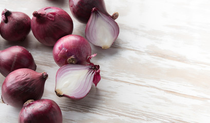 Fresh purple onions and one sliced onion on wood table