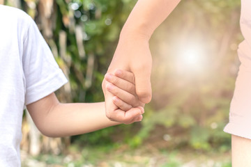 Fototapeta premium Mother and son holding hand on the background blurred nature. Love concept with parents and family.