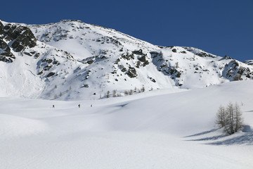 Obraz premium hiking up along sunny trail in amazing awesome winter day in the immensity of the mountain. Valle d'Aosta, italian alps.