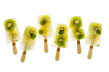 Fruit popsicles, homemade fruit ice lolly of various fruits; kiwi fruit and lime with the addition of fresh mint and citrus lemonade on a white background, top view. 