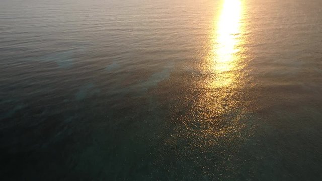 Tilt up aerial, sunset over ocean horizon