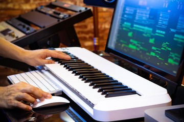 Obraz na płótnie Canvas male professional music producer hands arranging a song on midi keyboard and computer in home studio. music production concept