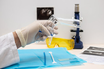 Doctor gynecologist preparing for pelvic examination with sterile vaginal speculum.  Health care concept. Woman health concept.