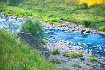 Summer Nature Landscape. Fast River and Old Ruined Stone Bridge on Shore