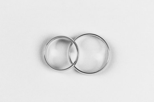 a pair of gold wedding rings on a white background, top view flat lay, black and white photo