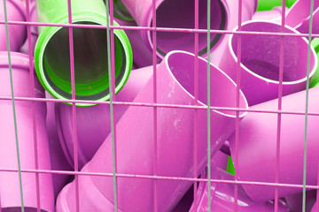 Ein Haufen kurzer Rohre aus Kunststoff liegt in einer Gitterbox.