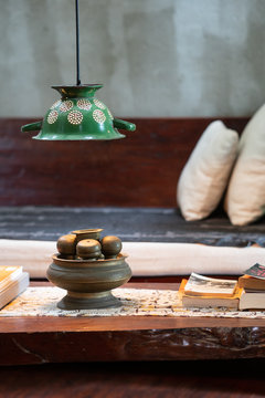 Wooden table with interesting books near bed with pillows in bedroom of ancient village house
