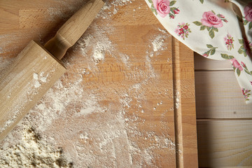 Rolling pin on pastry board sprinkled with flour on wooden  table