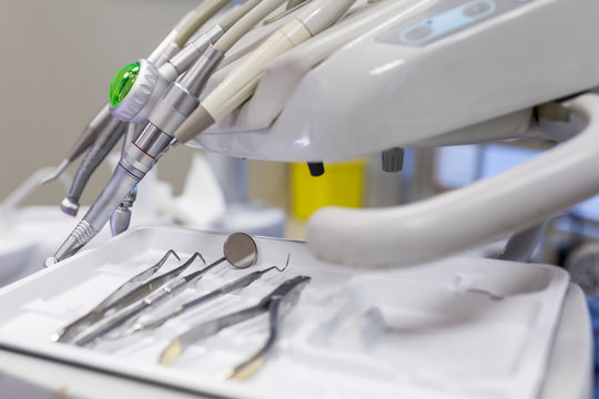 Dentist steel tools like sharp, scraper, carver, drill and mirror in tray on table in dental cabinet in clinic