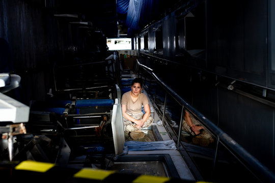 Attractive female soldier looking at camera while sitting inside dark hangar