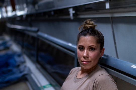 Attractive female soldier looking at camera sitting inside modern military transport