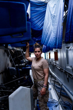 Attractive female soldier looking at camera while standing inside modern military transport