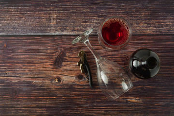 Dark bottle of wine and glasses on wooden background. Top view with copy space.