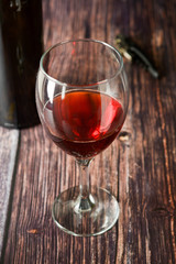 Glass of red wine over rustic, wooden textured table. Dark photo.