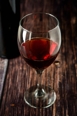 Glass of red wine over rustic, wooden textured table. Dark photo.