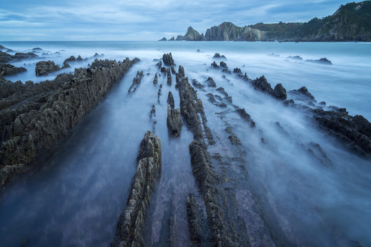 Beautiful seascape of Playa de Gueirua beach with rocks on misty day at Asturias, Spain