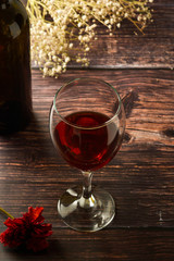 Glass of red wine over rustic, wooden textured table. Dark photo.