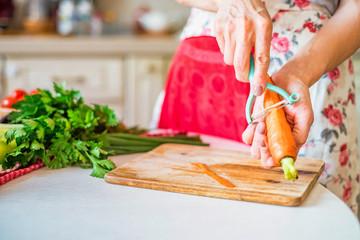 Female hand with peels carrot in kitchen. Cooking vegetables