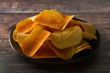 Potato chips over wooden background. Salty crispy snack.