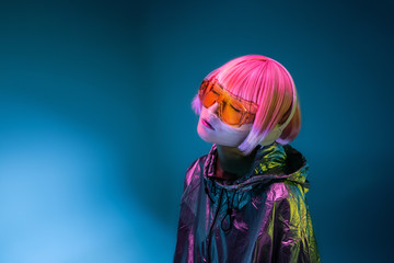 Young Asian woman with stylish pink haircut and sparkly silver jacket standing and listening music